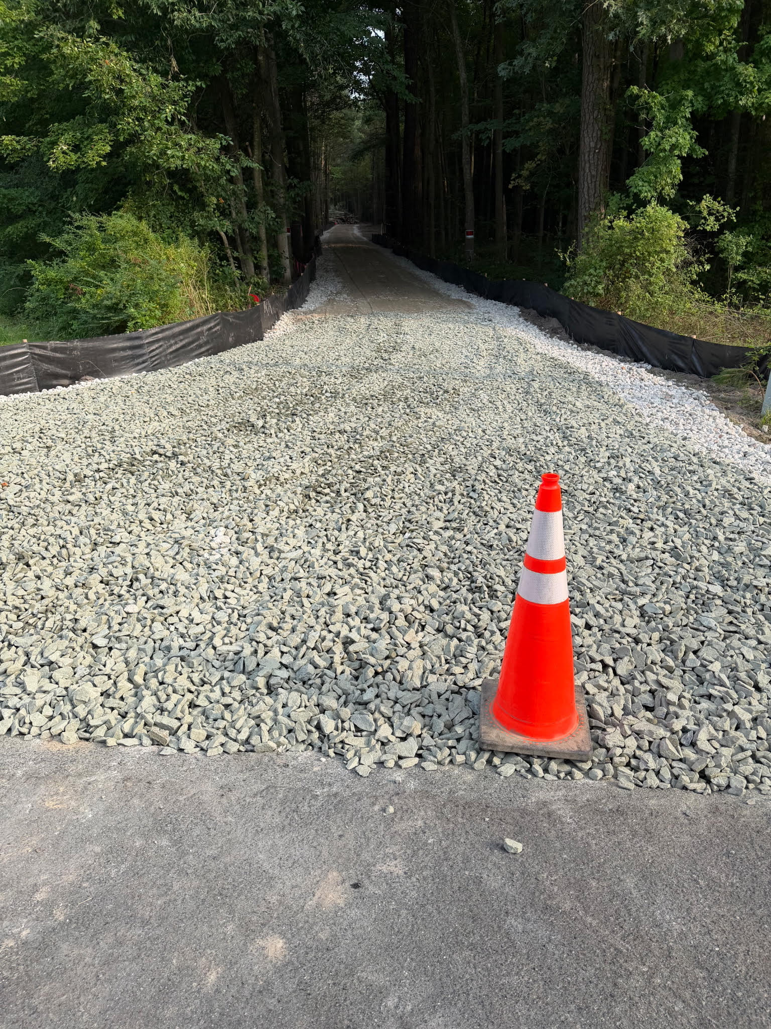 Stone site entrance at Somerset with black silt fencing along the wooded access road